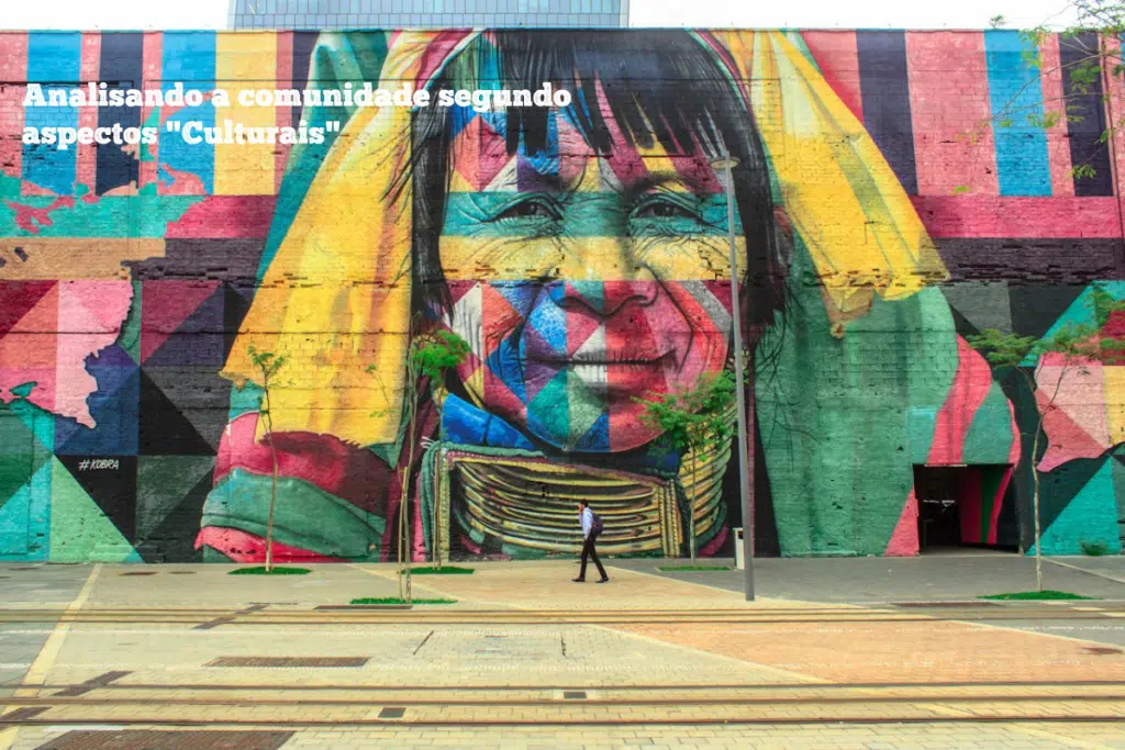 Un hombre va caminando frente a un gran graffitti en colores donde se retrata a una persona.