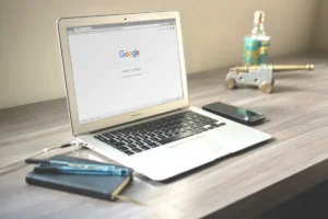 Computador sobre una mesa, tiene una ventana abierta que deja leer "Google"