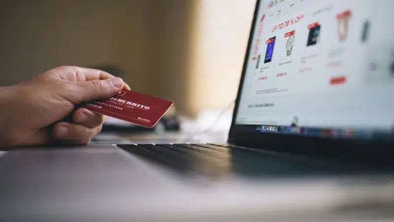 Persona sostiene una tarjeta frente a un computador.