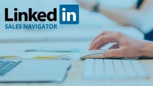 Una mano sostiene un mouse en un escritorio junto a un teclado y notebook.